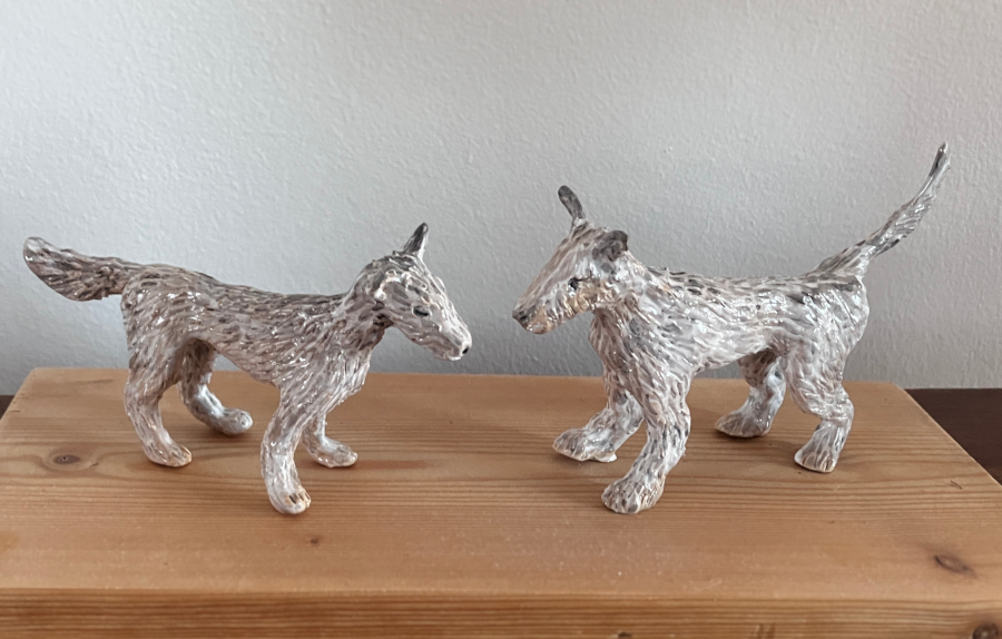 Two ceramic dogs on a wooden base.